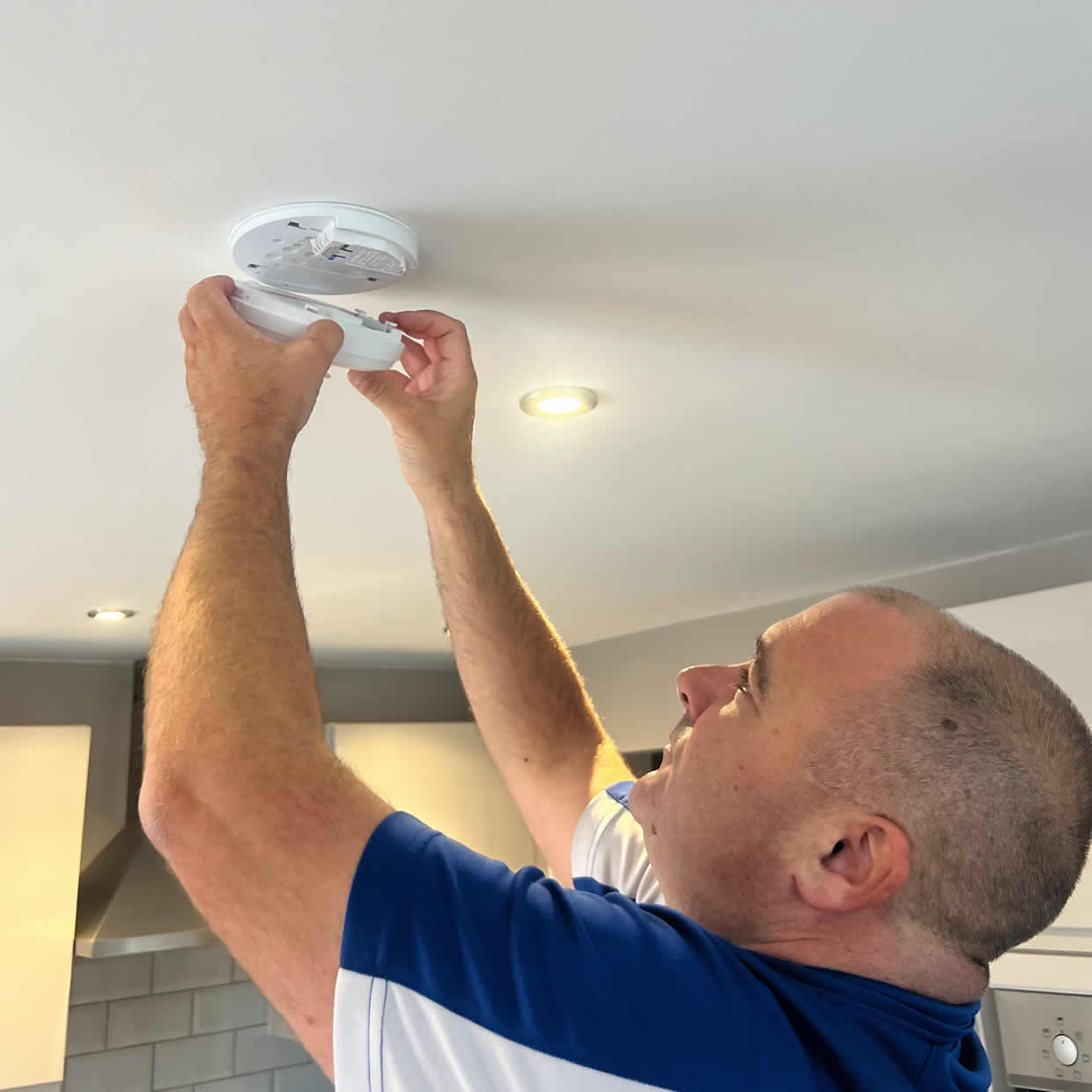 Smoke alarm installer fitting an alarm in a Crewe property